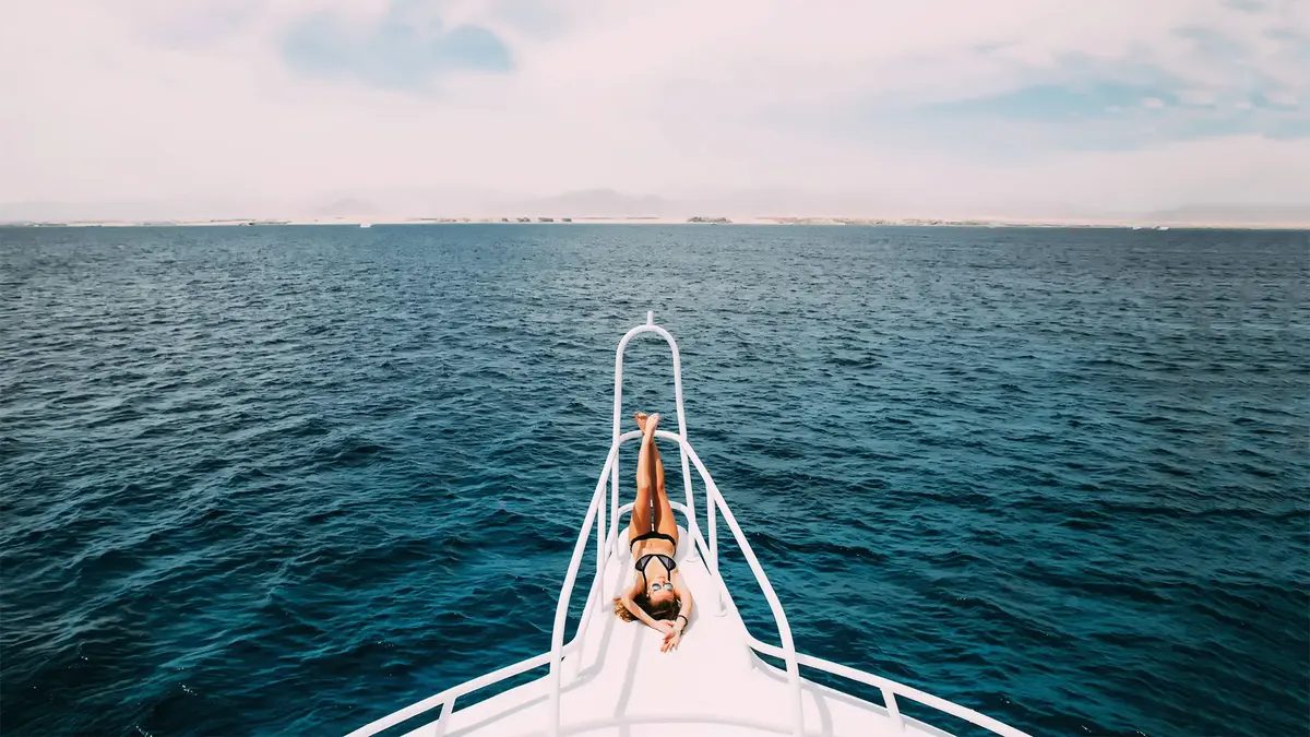 A woman sunbathing at the tip of a boat.