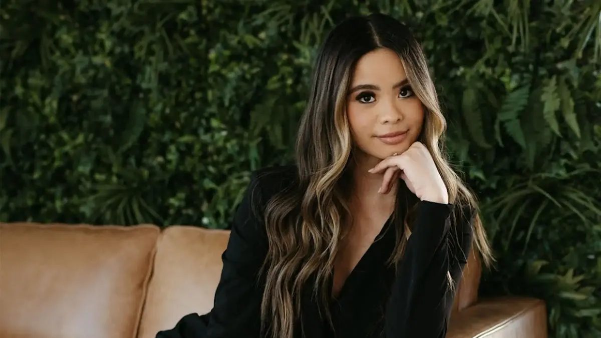 Minty Bets sitting on brown leather sofa with foliage in background