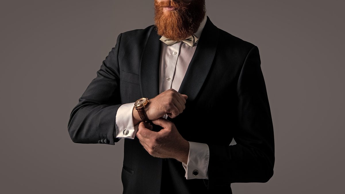 tuxedo fashion. cropped view of bearded man in tuxedo with wrist watch isolated on grey background